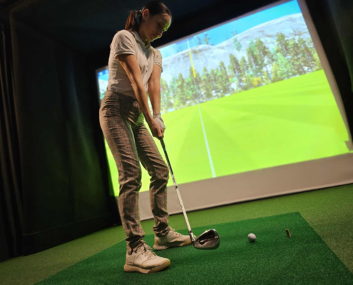 New golfer receiving beginner golf coaching on swing basics at indoor facility