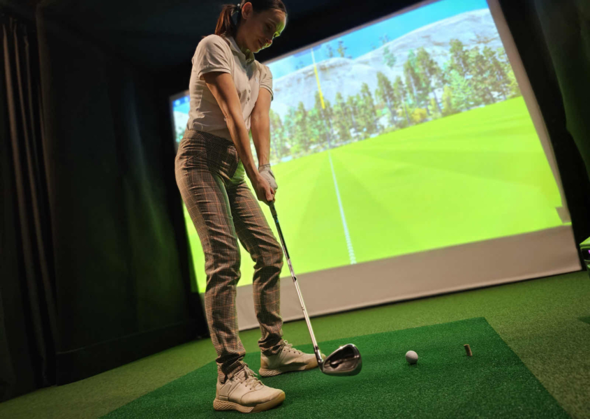 New golfer receiving beginner golf coaching on swing basics at indoor facility