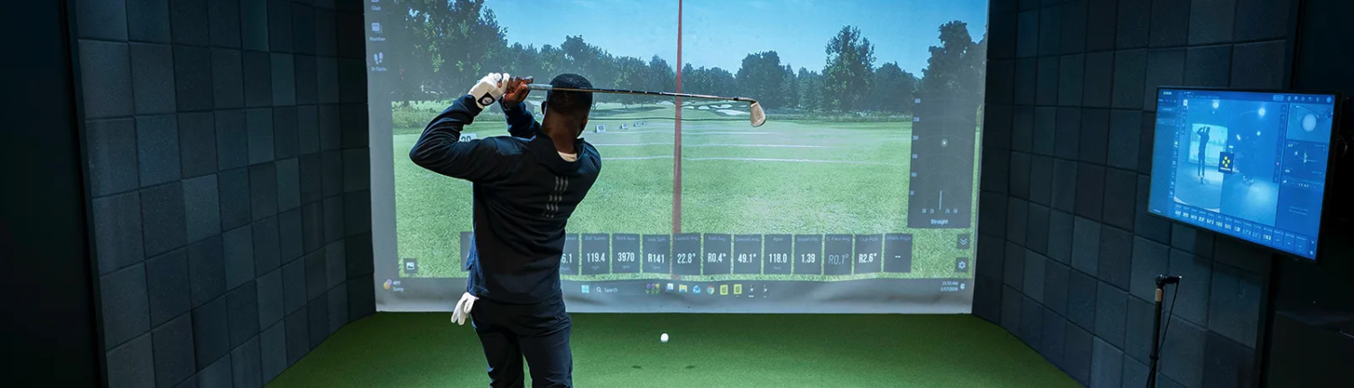 Man swinging in golf simulator using his golf membership Man swinging in golf simulator using his golf membership