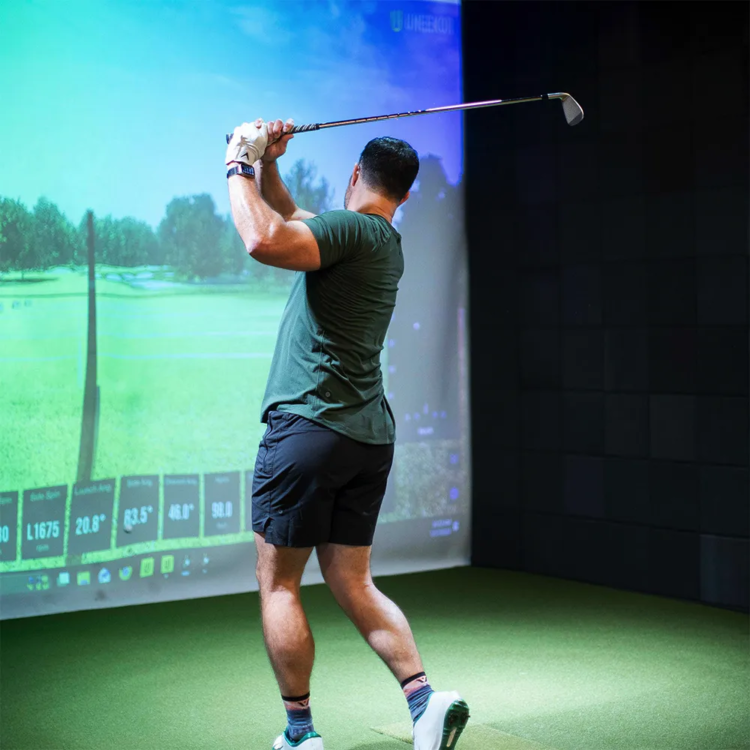 Man swinging on the golf simulator during a lesson