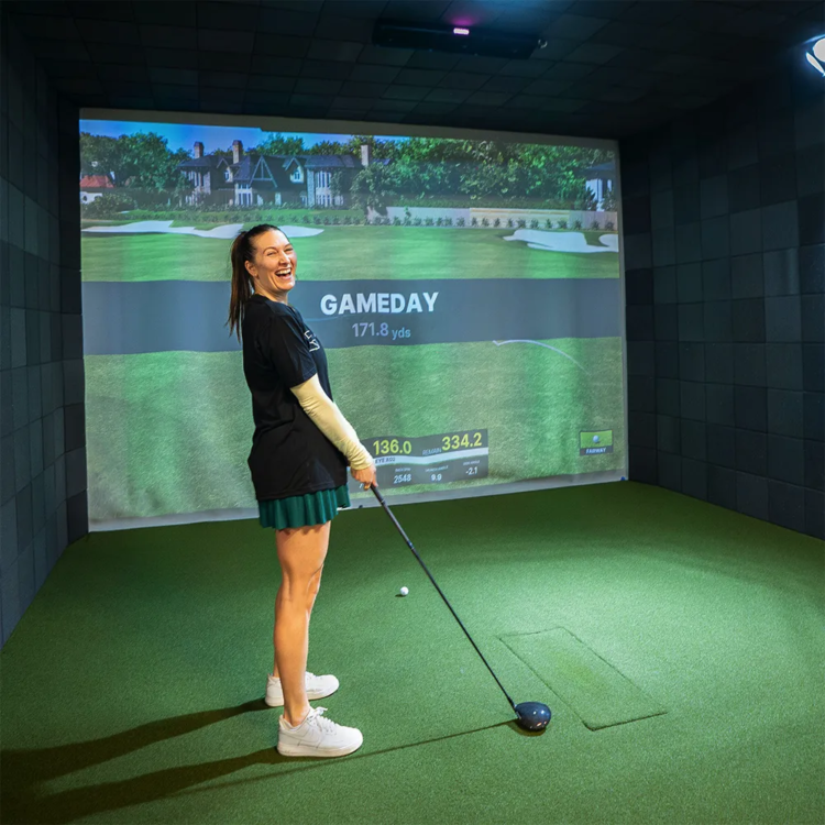 Smiling woman excited to be playing golf in a simulator