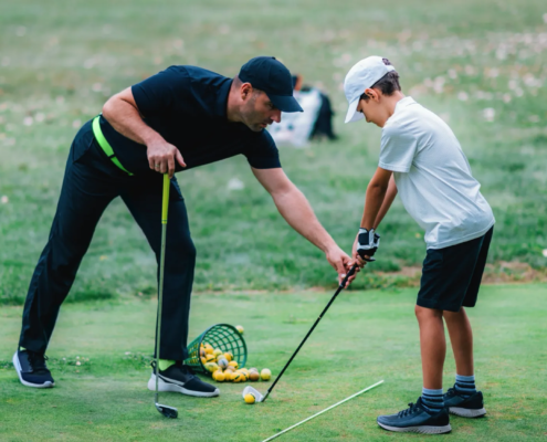 Golf instructor teaching grip and posture to child during junior golf lessons