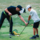 Golf instructor teaching grip and posture to child during junior golf lessons
